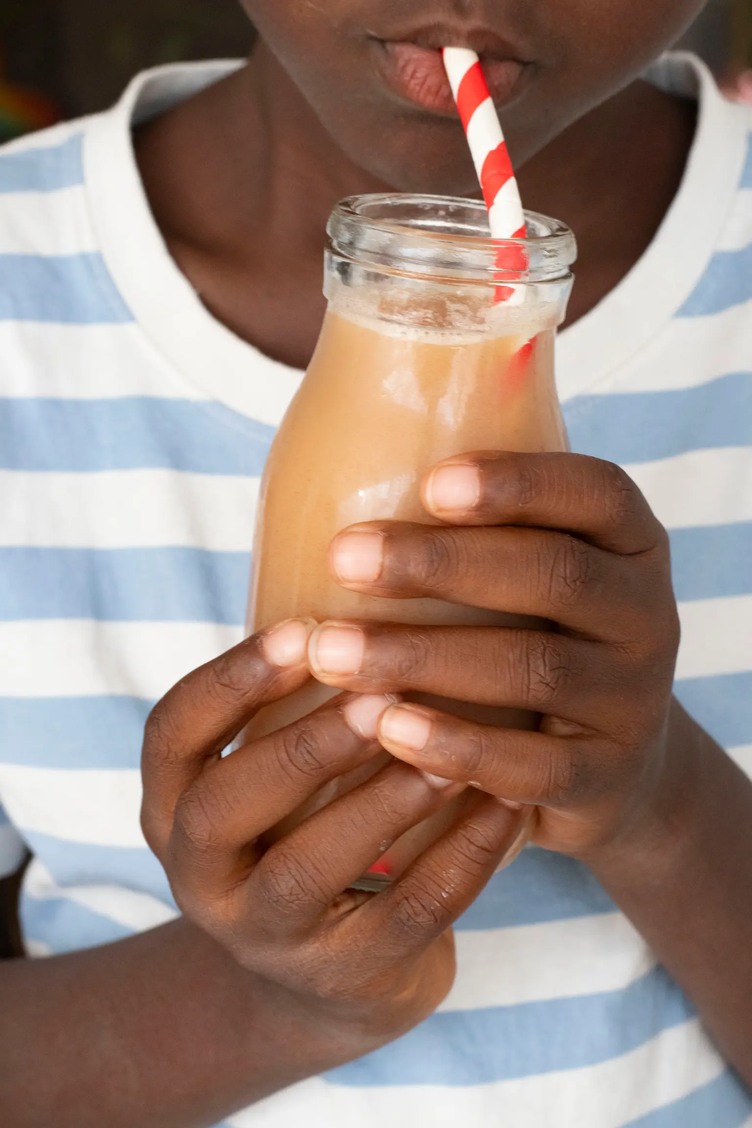 enfant qui tient une bouteille de jus de bouye